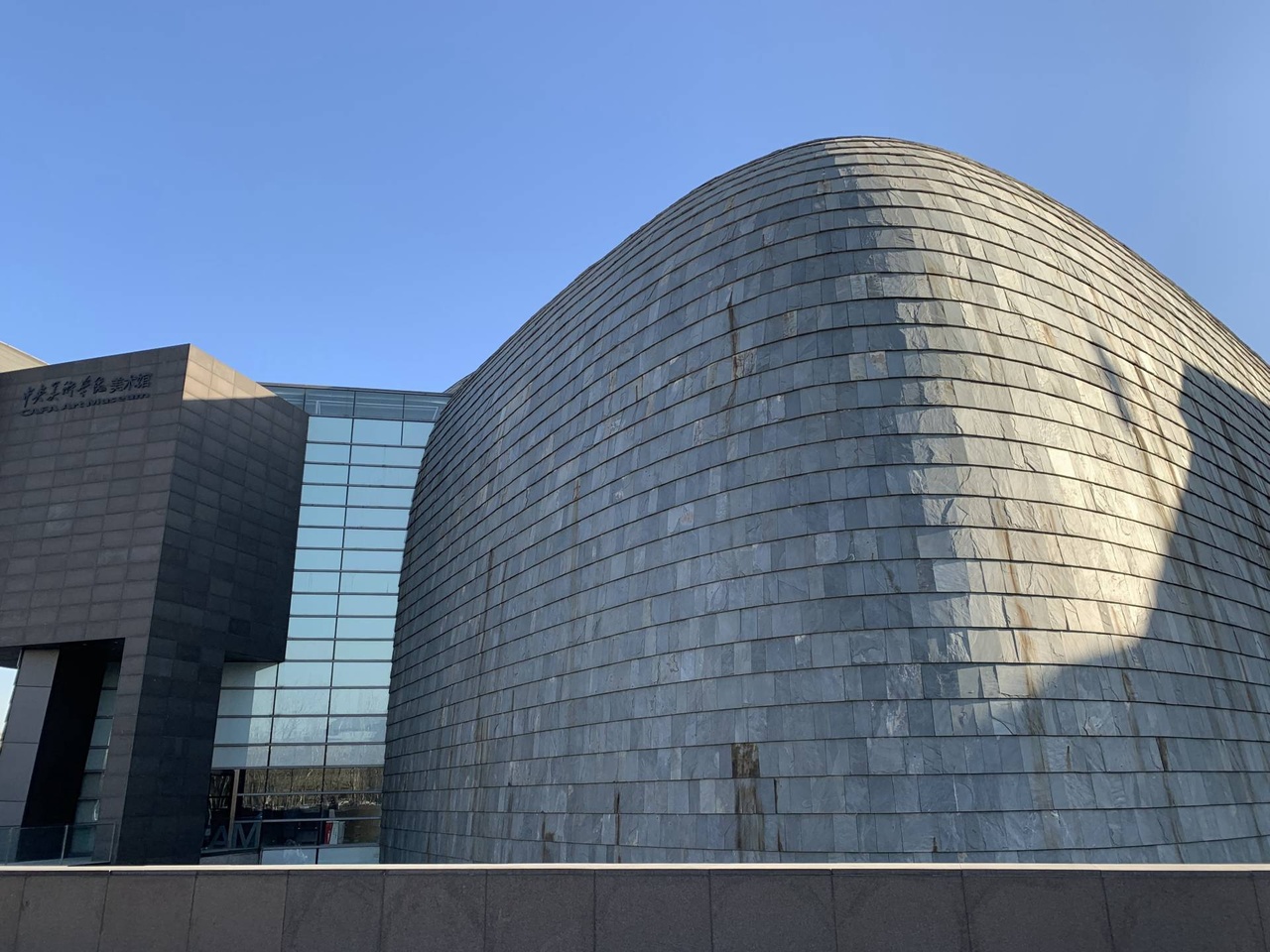 美術館外面迴旋鏢形狀，石材幕牆與屋頂曲線，形成三個類似立體迴旋鏢外殼體，像巨型蒙古包或愛斯基摩房屋，又像「鯊魚頭」。<br>圖：張錦滿攝影