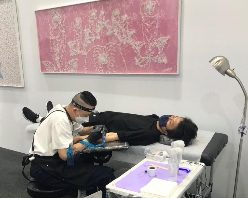台灣亞紀畫廊推出侯俊明的花布個展,現場有師傅為現場觀眾刺上圖案。